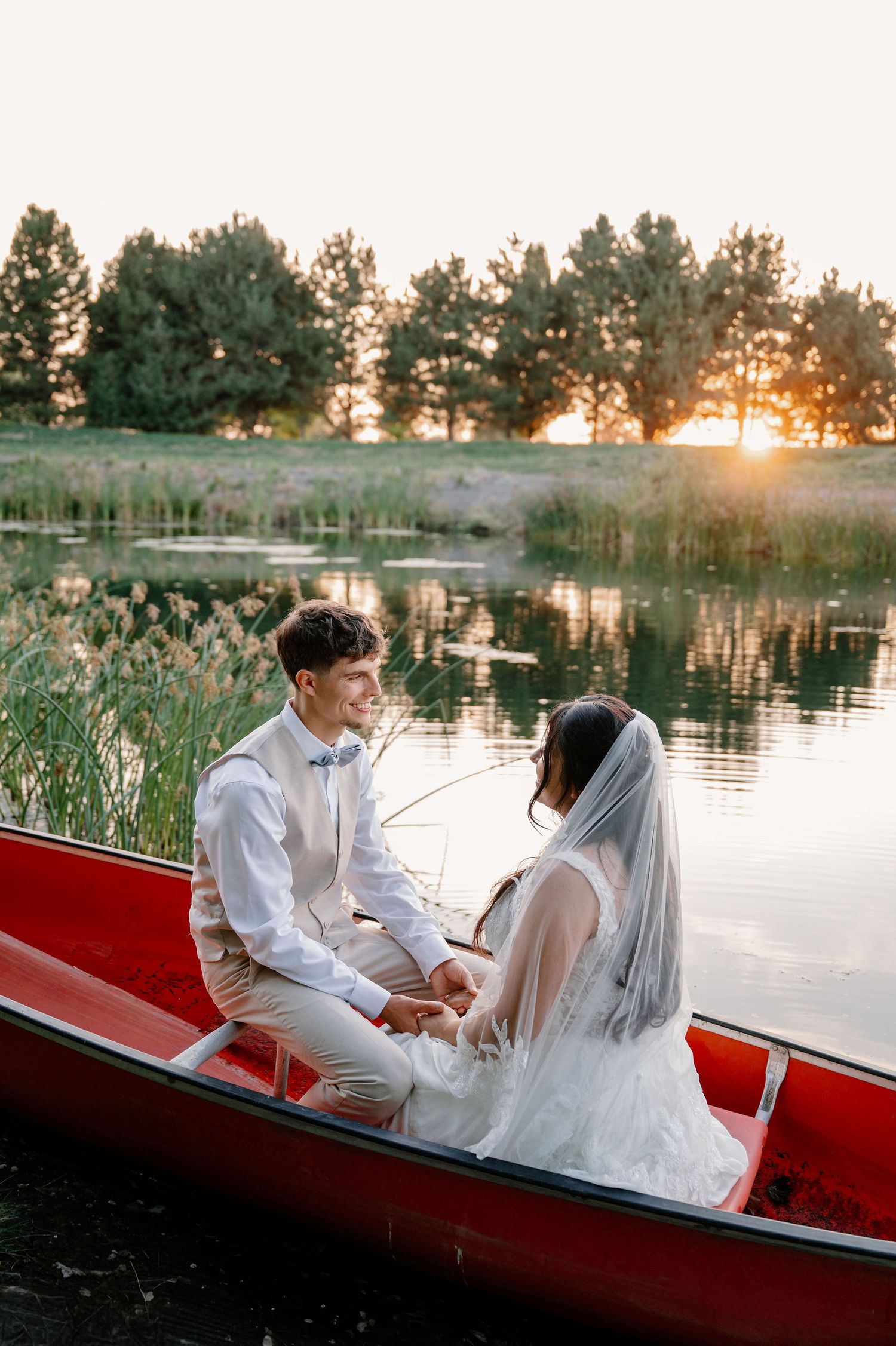 Sunset bride and groom portraits in a canoe on a pond