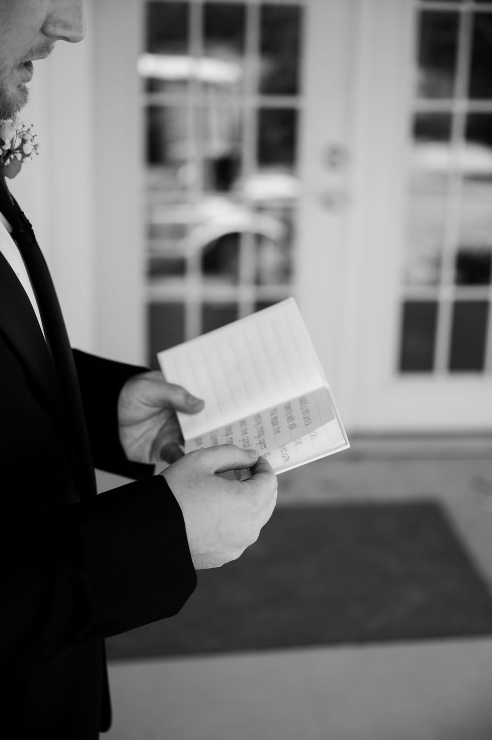Close-up black and white shot of hands holding handwritten vows or notes.