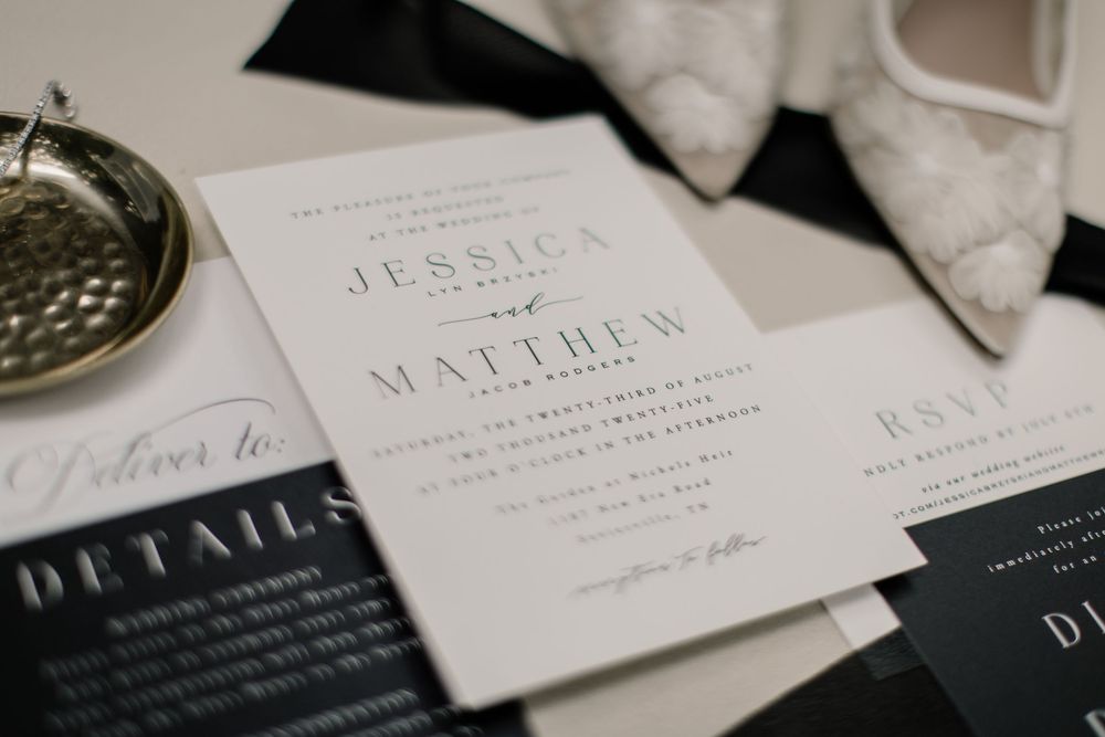 Elegant wedding invitation suite with classic typography and minimalist design displayed alongside white shoes.