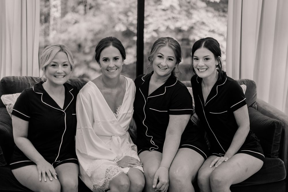 Wedding party relaxes together on couch during pre-ceremony preparations.