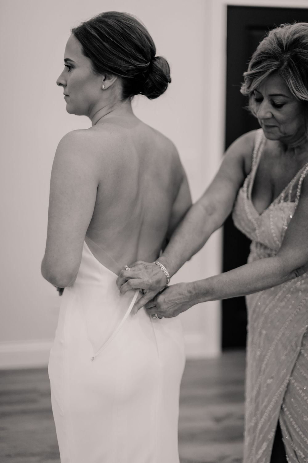 Black and white series showing final dress adjustments before the wedding ceremony.