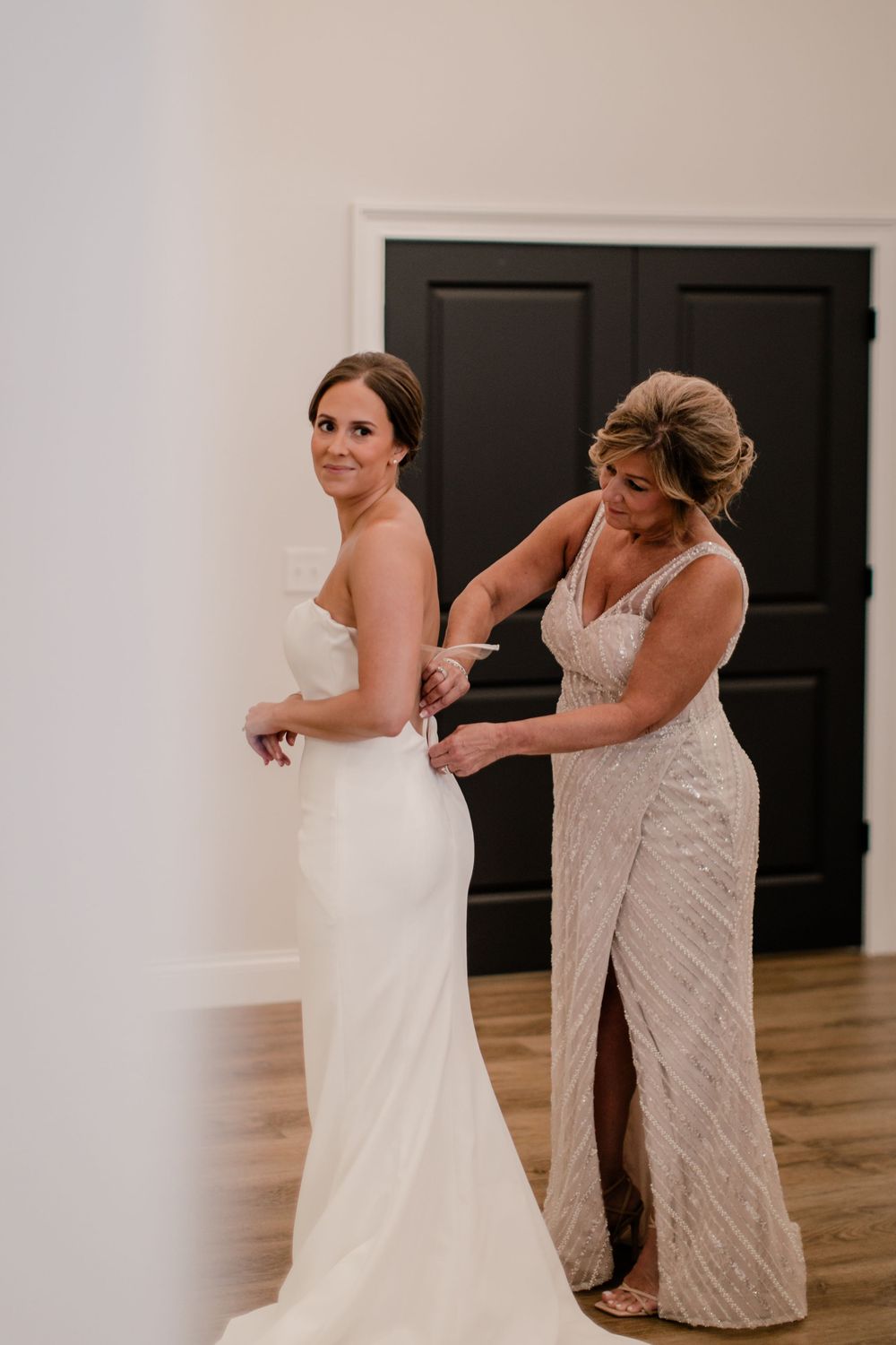 Behind-the-scenes moment of wedding dress preparations in a bright indoor space.