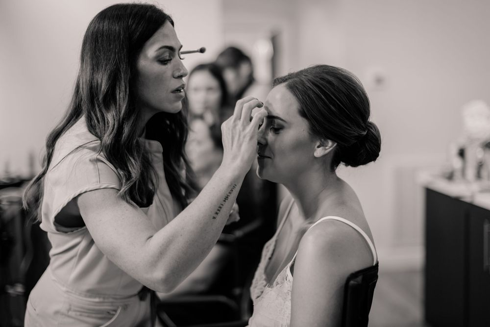 Getting ready moments captured in black and white as makeup is applied before the wedding.