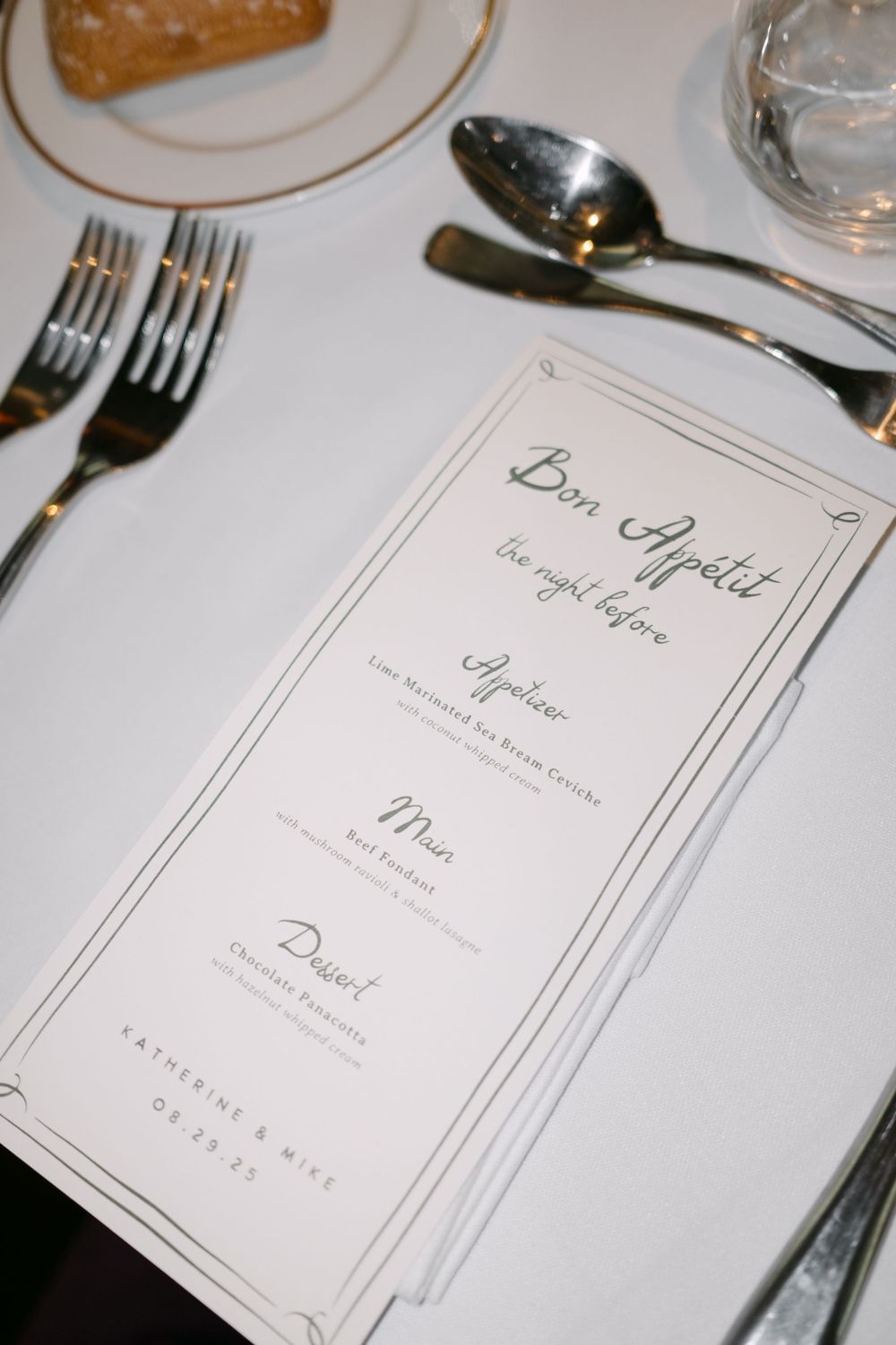 Elegant wedding menu card that says 'Bon Appetit' placed on a formal table setting with silverware.