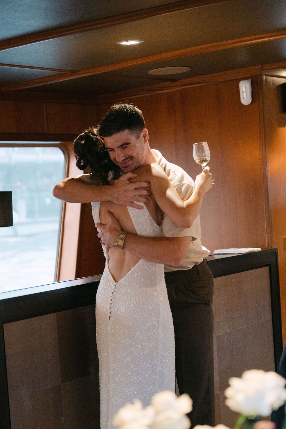 A romantic moment captured at a wedding as a couple embraces in a wood-paneled room.