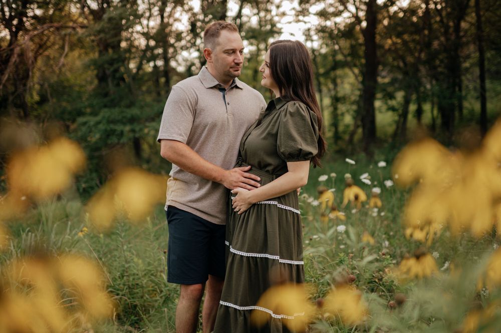 Couple sharing a tender moment in a wildflower meadow, woman in olive dress, man in beige polo.