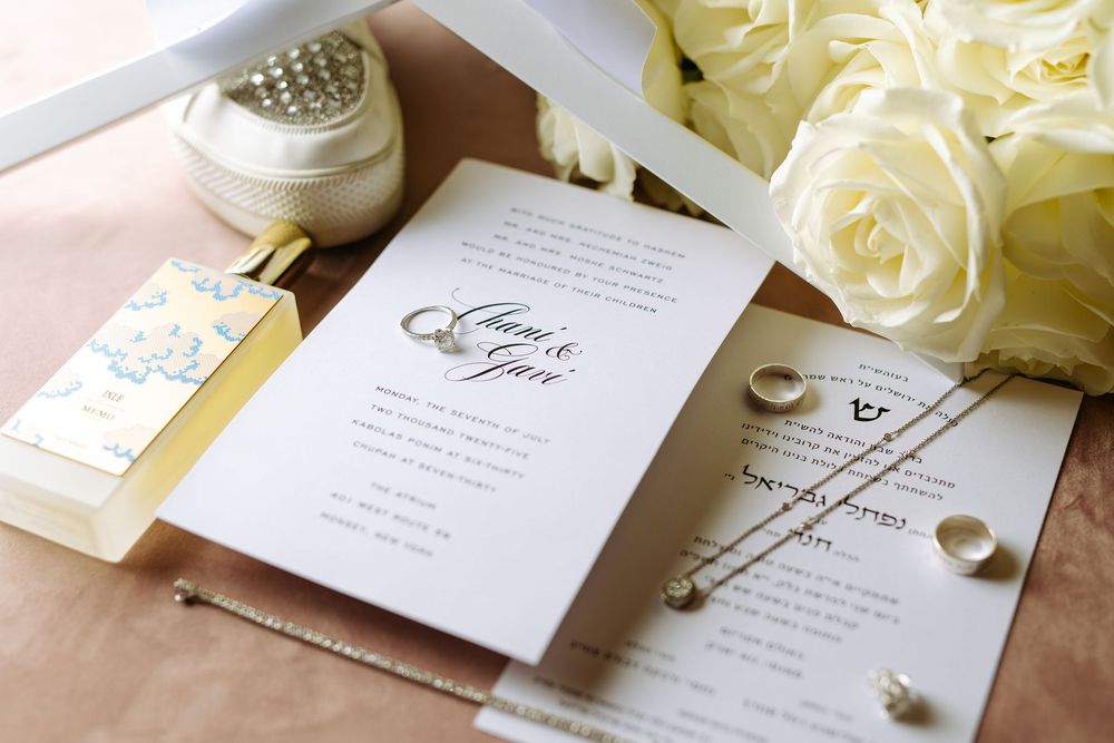 Elegant wedding invitation suite with white roses and delicate calligraphy on cream colored paper.