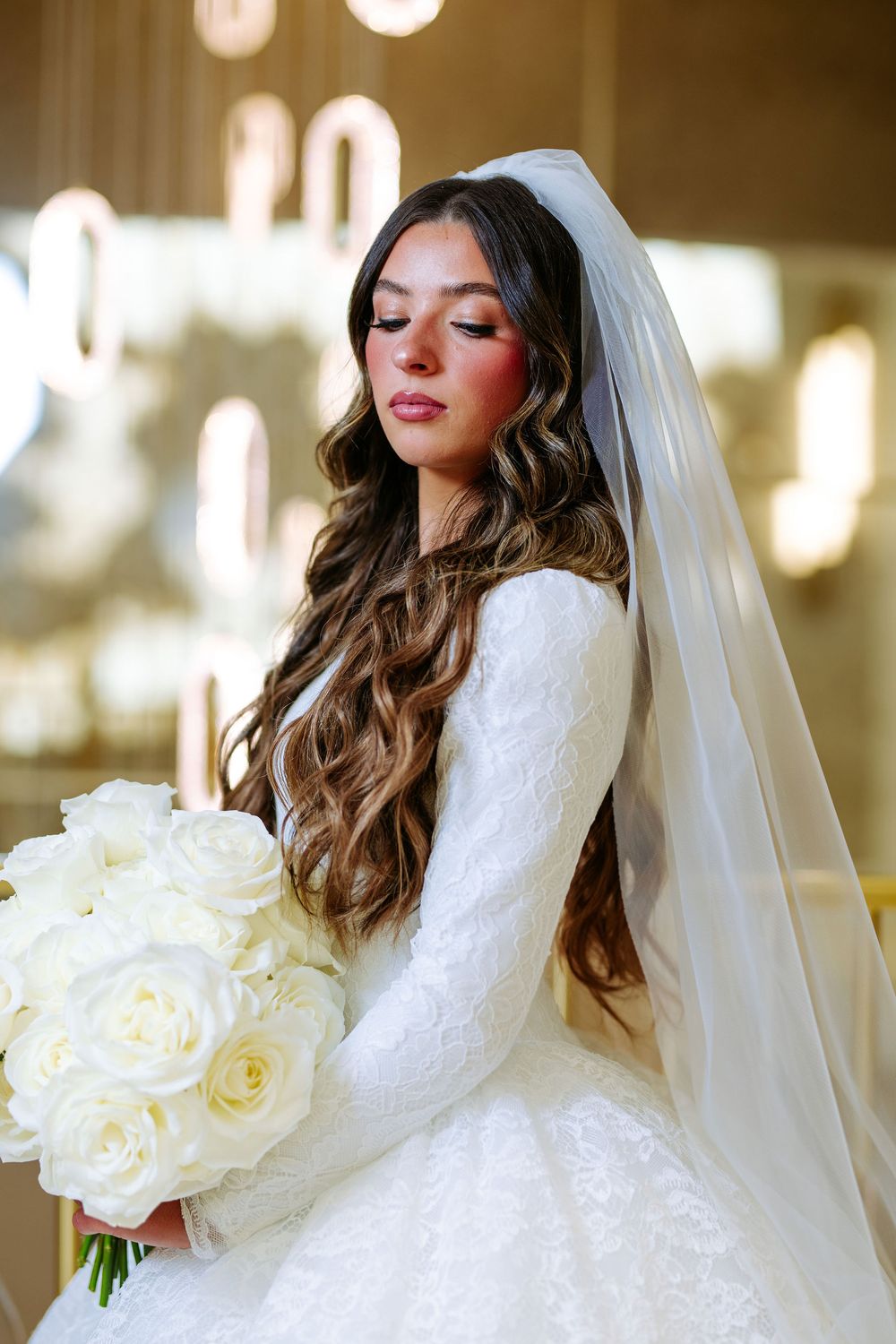 Elegant bridal portrait series featuring a white wedding gown, flowing veil and white rose bouquet against a warm glowing backdrop.