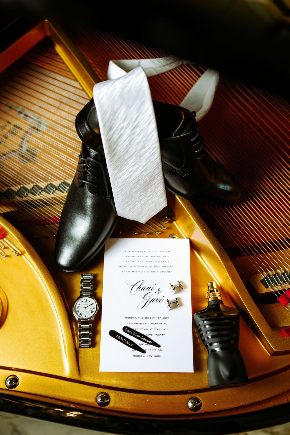 Black dress shoes and wedding invitation rest elegantly on a yellow piano's curved surface in dramatic lighting.