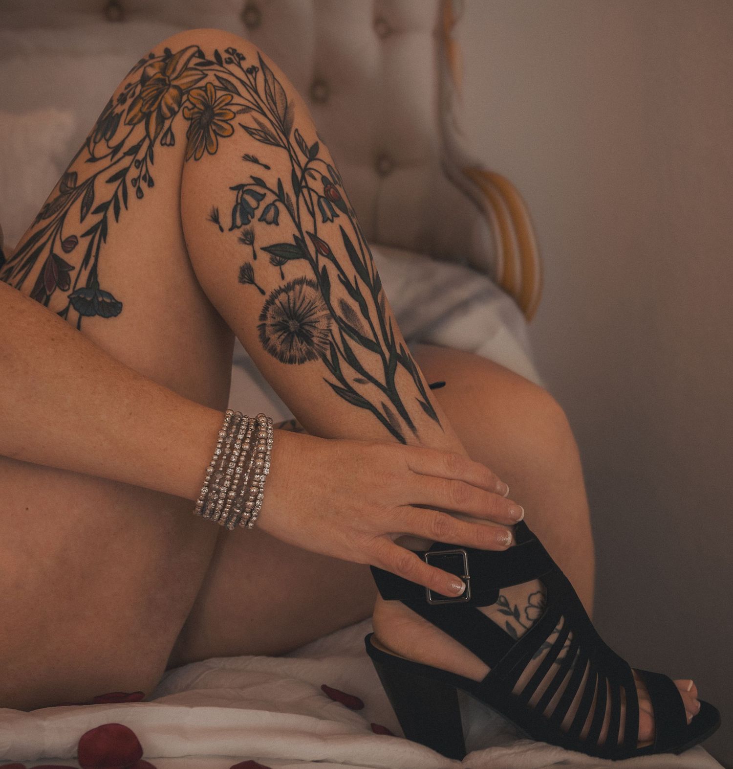 Close-up view of hands with tattoos and jewelry during a massage therapy session on a beige surface.