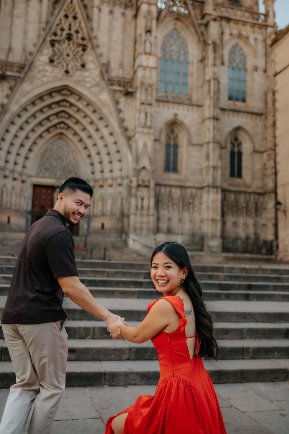Wide shot of couple in front of historic architecture in Barcelona Old City for engagement announcement.