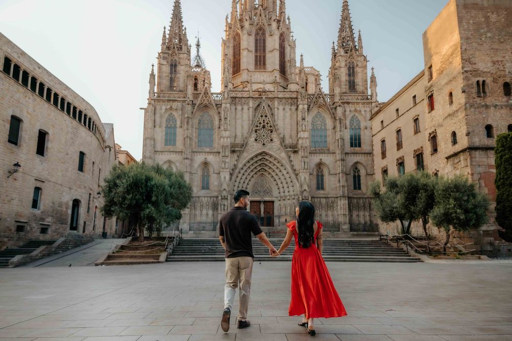 Wide shot of couple in front of historic architecture in Barcelona Old City for engagement announcement.