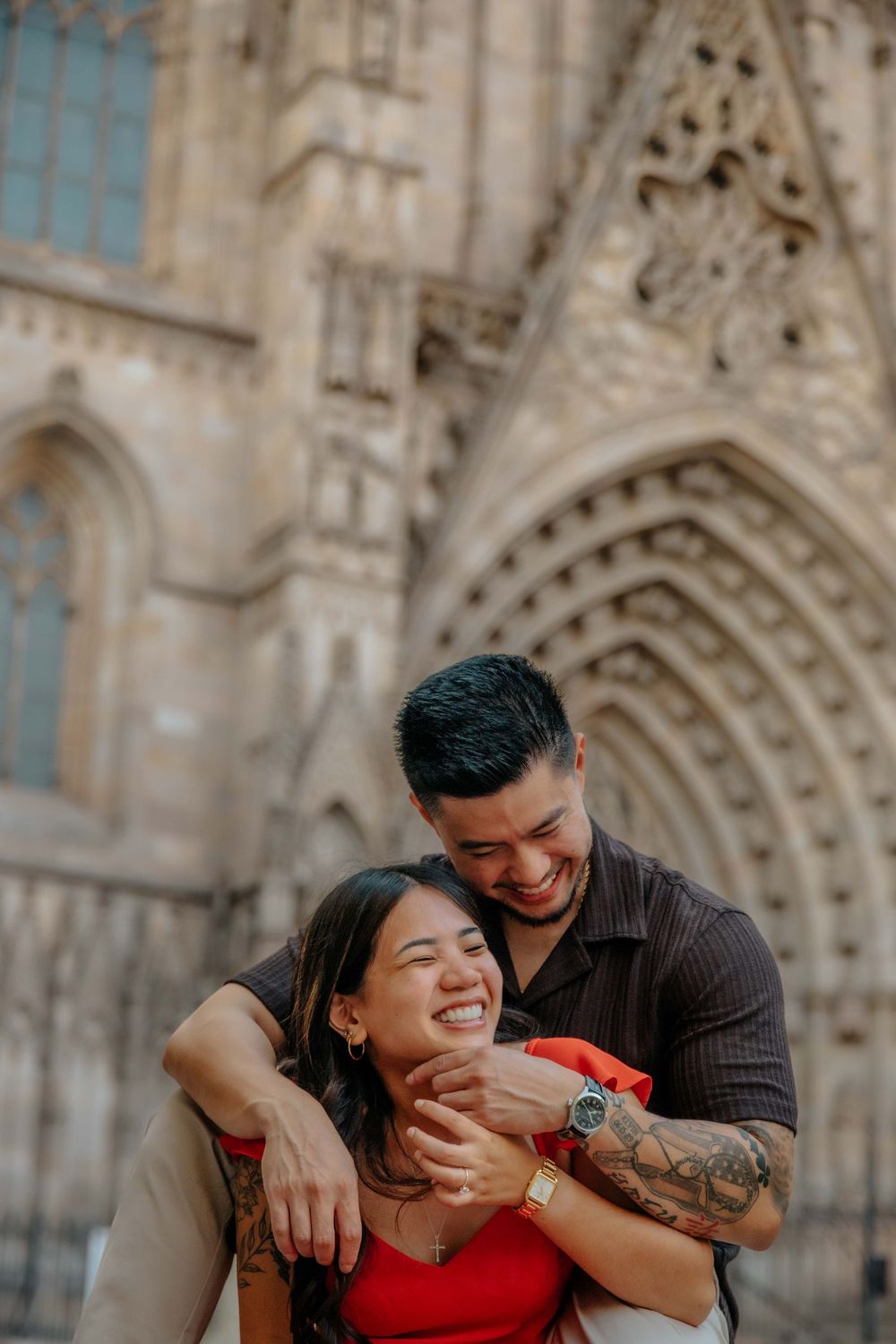 Wide shot of couple in front of historic architecture in Barcelona Old City for engagement announcement.
