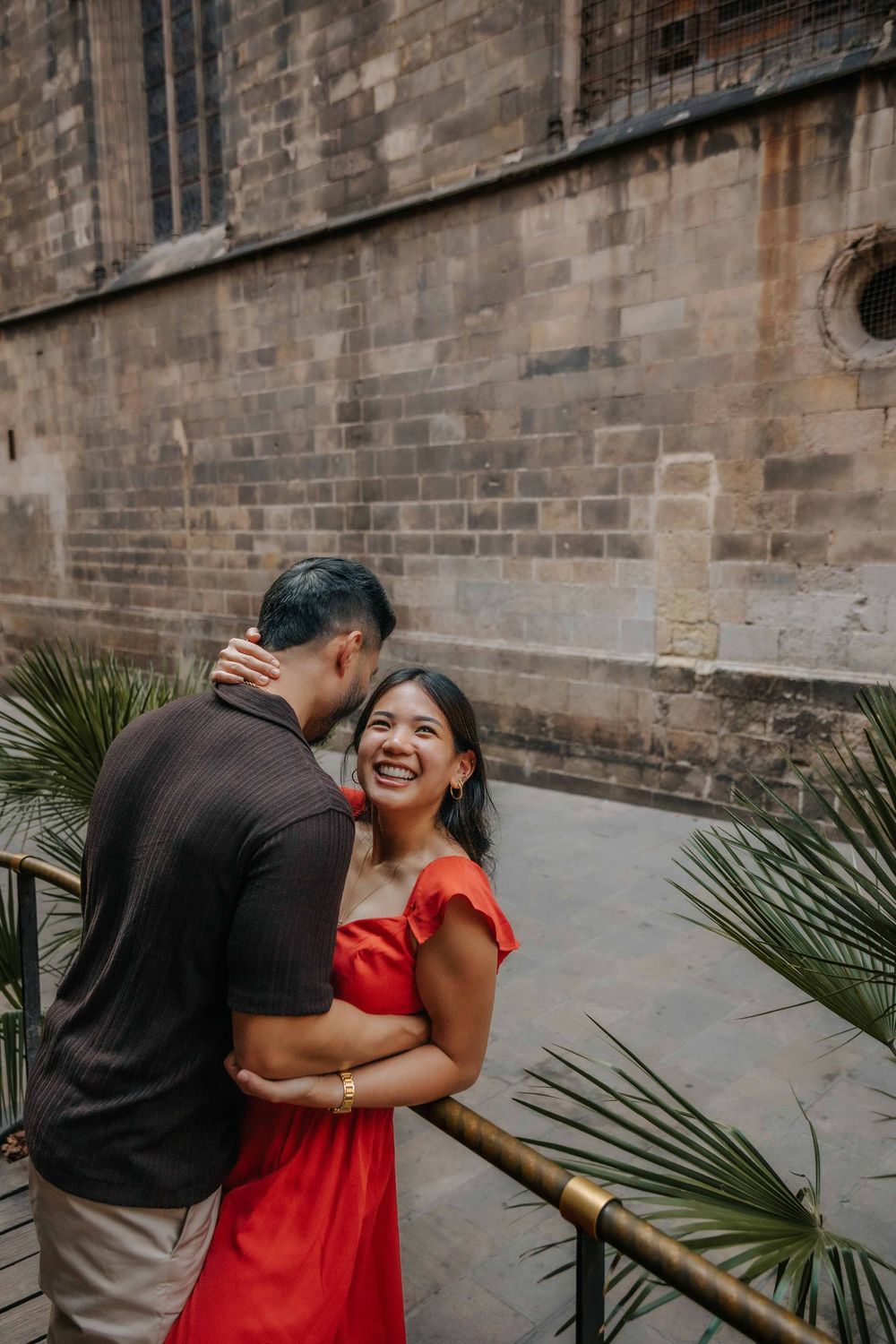 Wide shot of couple in front of historic architecture in Barcelona Old City for engagement announcement.