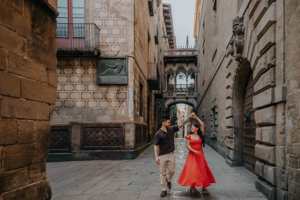 Wide shot of couple in front of historic architecture in Barcelona Old City for engagement announcement.
