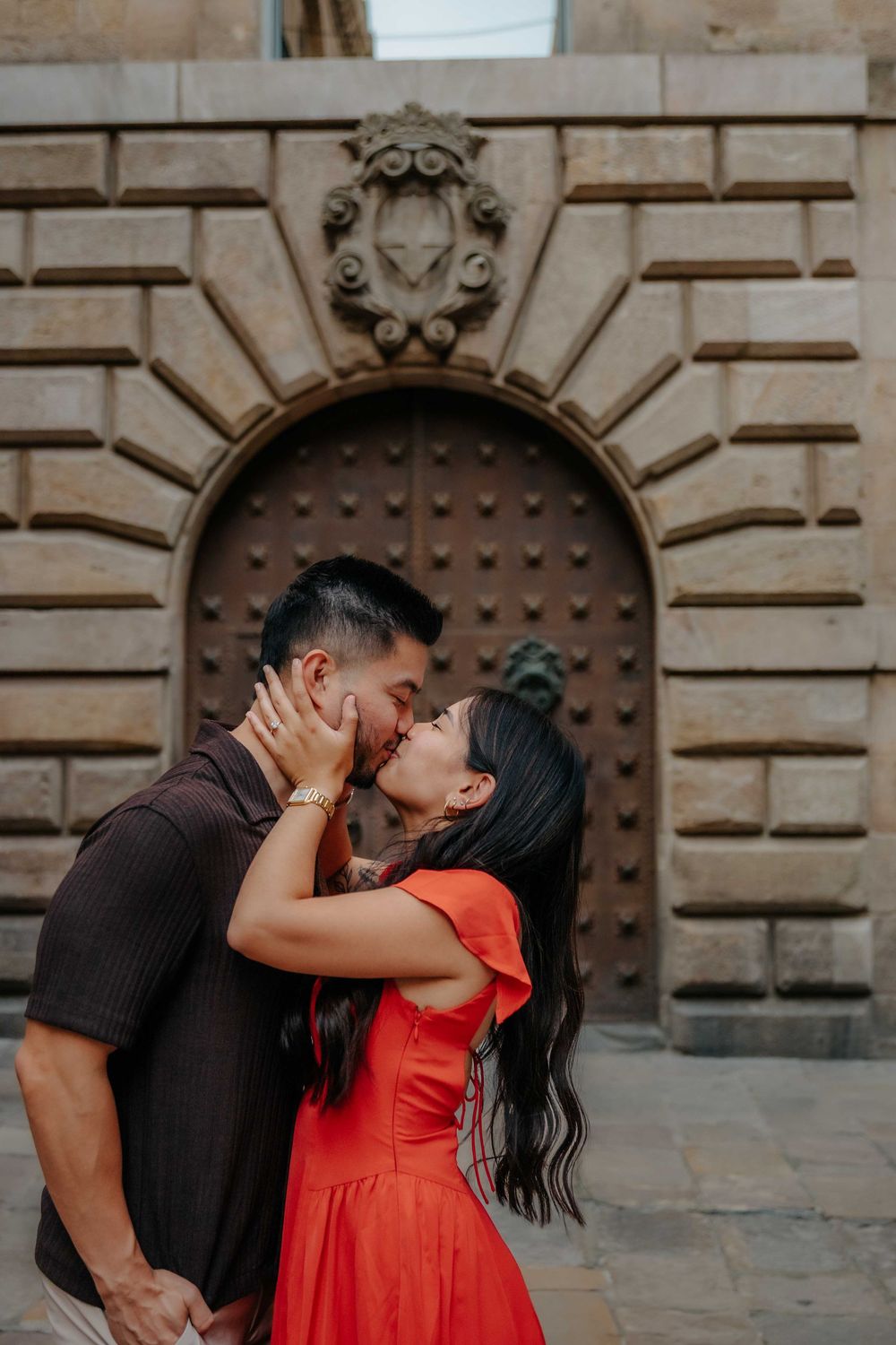Wide shot of couple in front of historic architecture in Barcelona Old City for engagement announcement.