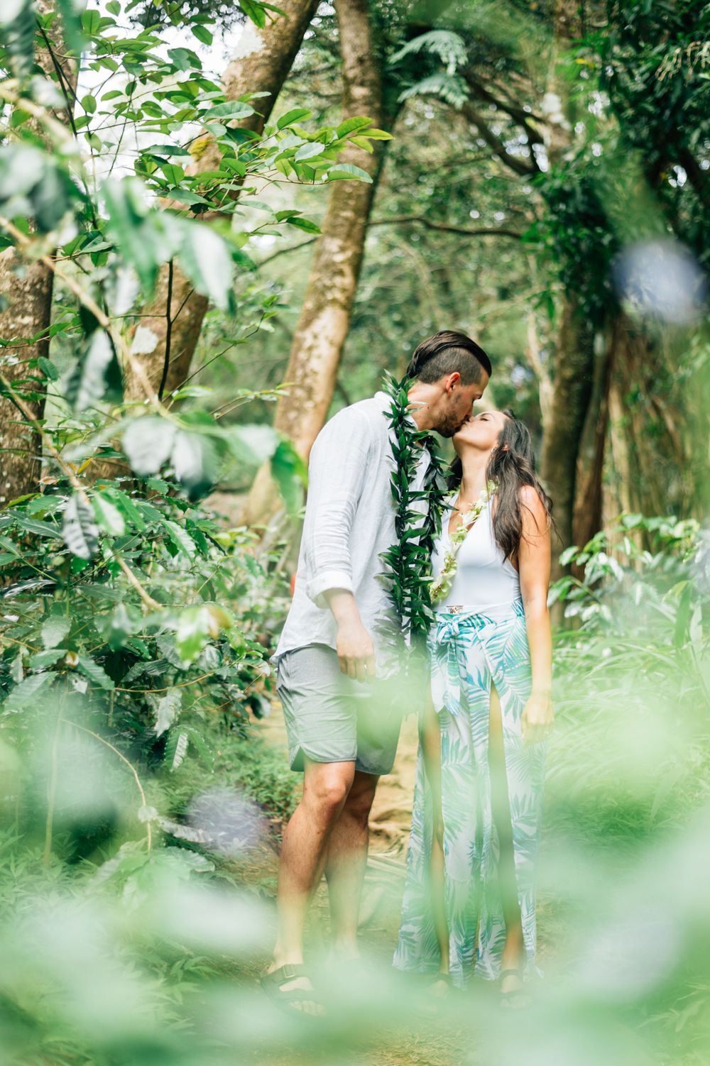 A romantic moment captured between two people in a verdant garden setting.