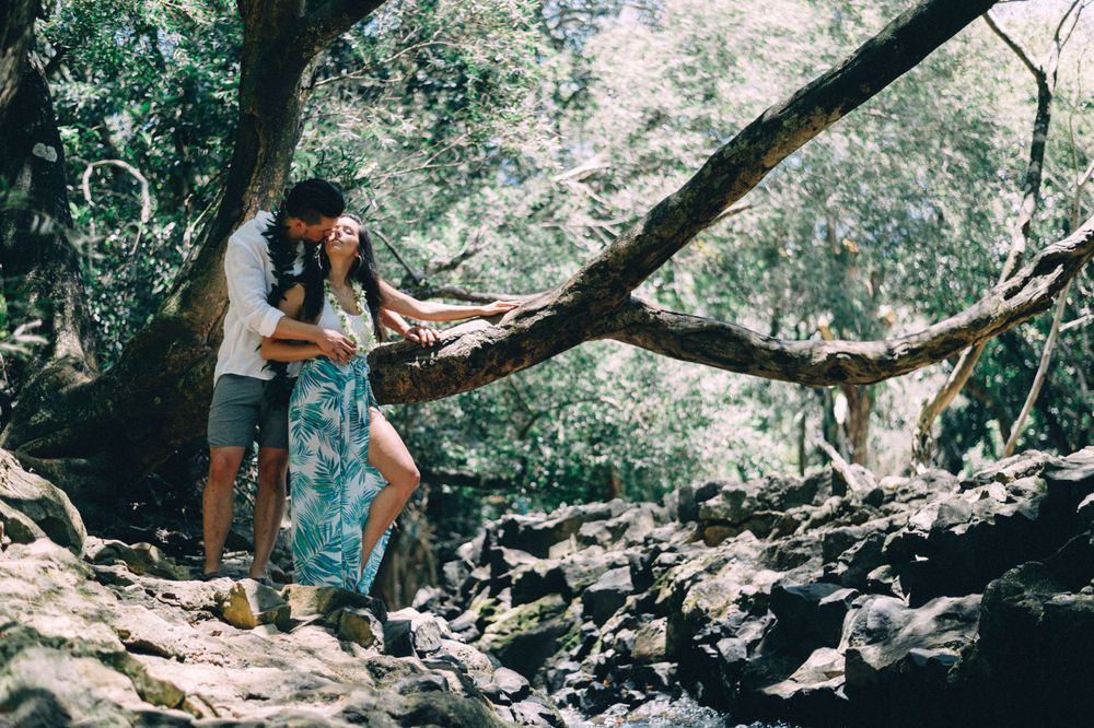 Couple walking along a rocky forest trail surrounded by tropical foliage.