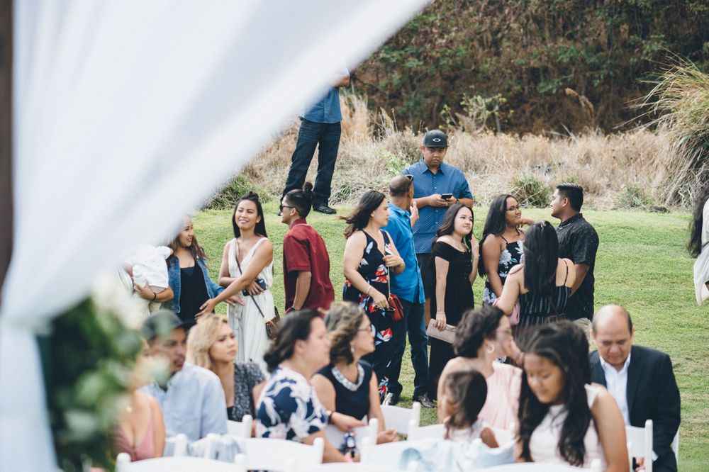 Wedding guests gathered on a grassy hillside for an outdoor celebration.