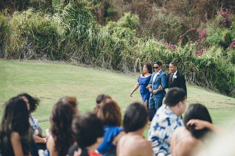 Outdoor wedding ceremony setup on a grassy hillside with natural landscaping.