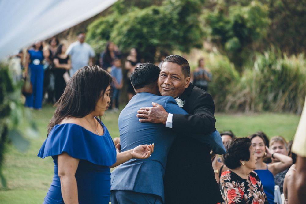 Wedding processional on a green lawn with guests watching from white chairs.