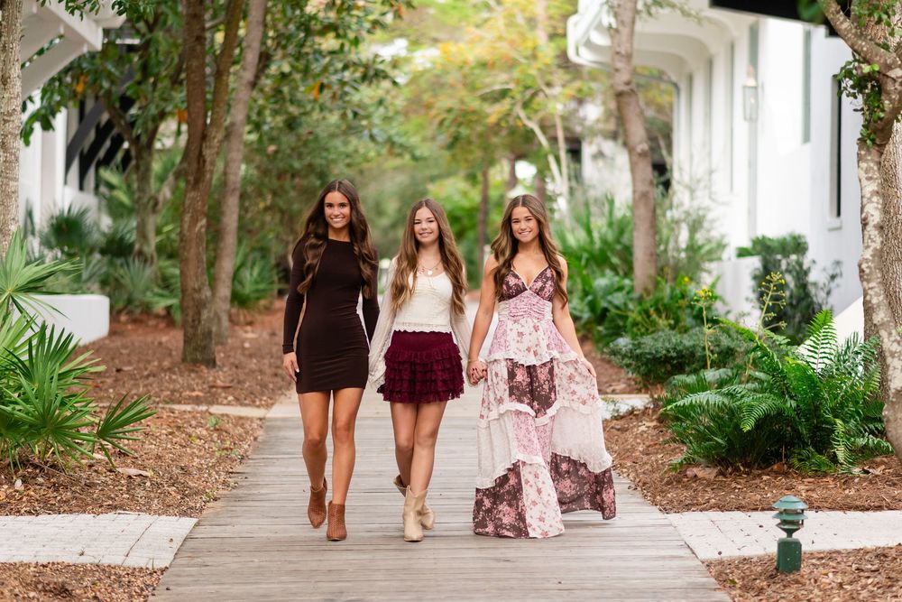 Four people walking together on a tree-lined path in a scenic outdoor setting.
