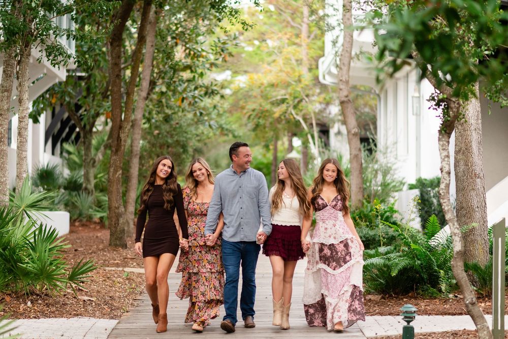 A group of people walking together through a lush garden path with trees and greenery in the background.