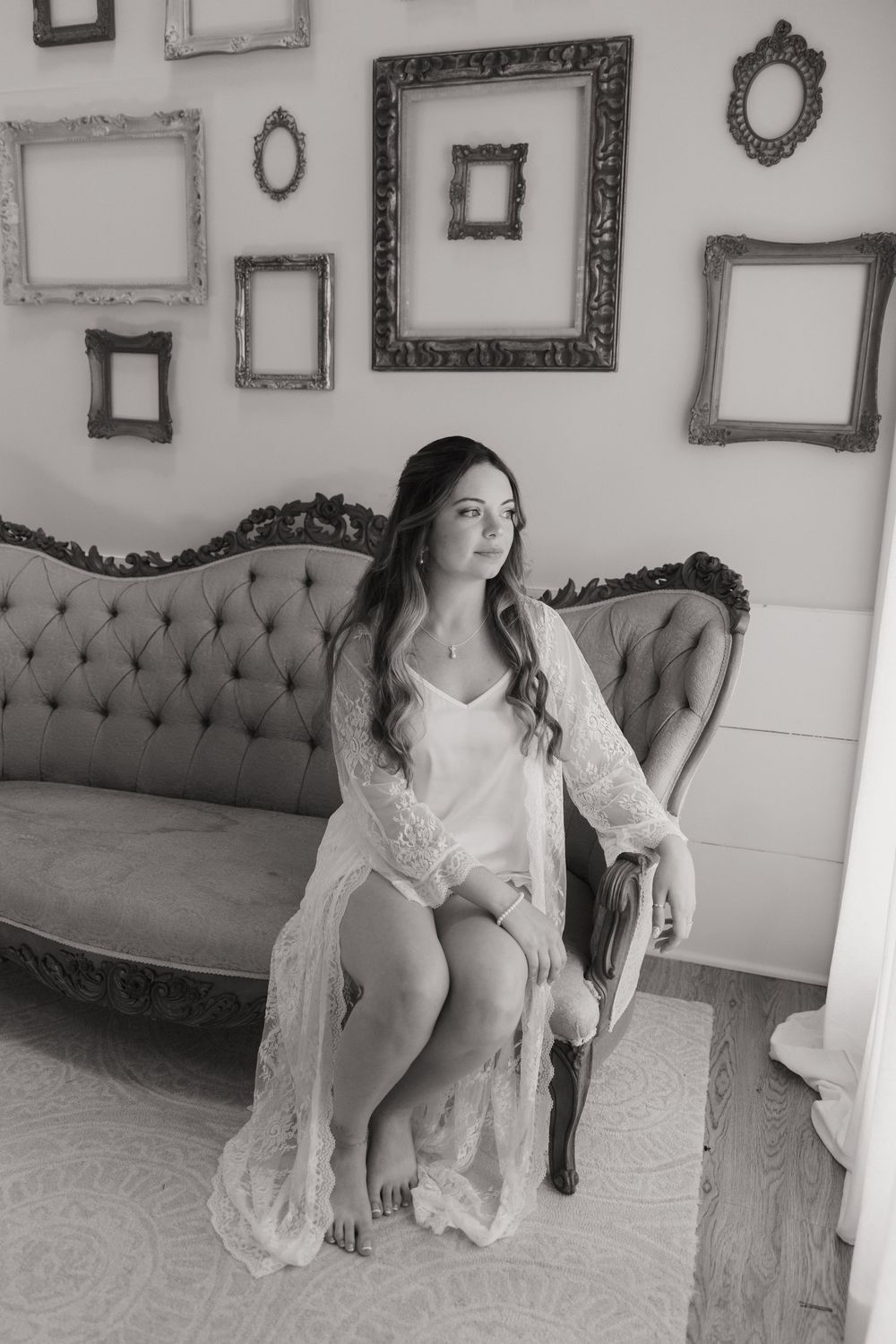 Black and white artistic portrait series showing reclining poses on an elegant tufted sofa with vintage frames on wall.