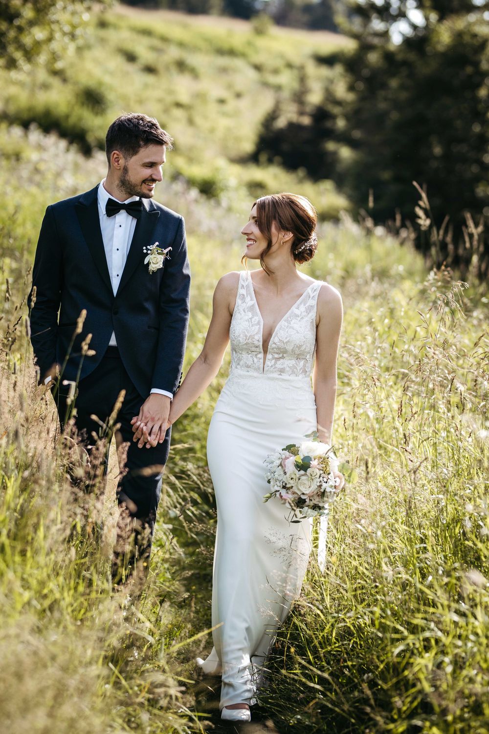 Wedding couple shares intimate moments in a sunlit meadow with tall golden grasses on their special day.