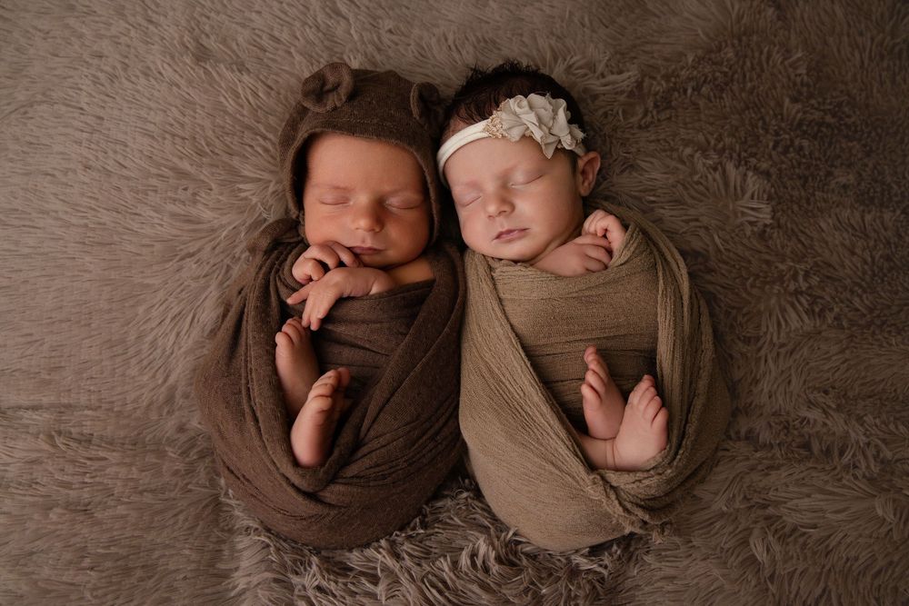 Four similar photographs of a sleeping newborn baby swaddled in brown and beige wraps on a textured backdrop.