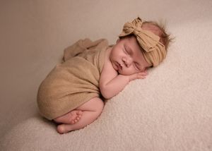 Peaceful newborn baby sleeping on soft beige blanket in minimalist photography series.