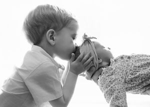 Black and white photo capturing sweet interaction between two young children.