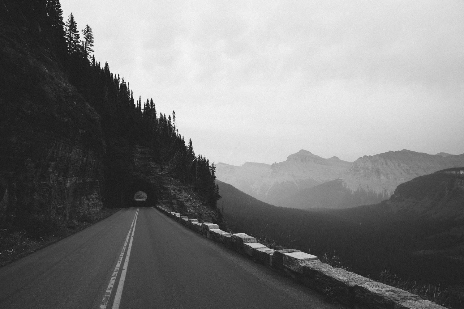 A series of black and white landscape photos showing winding mountain roads through evergreen forests and peaks.