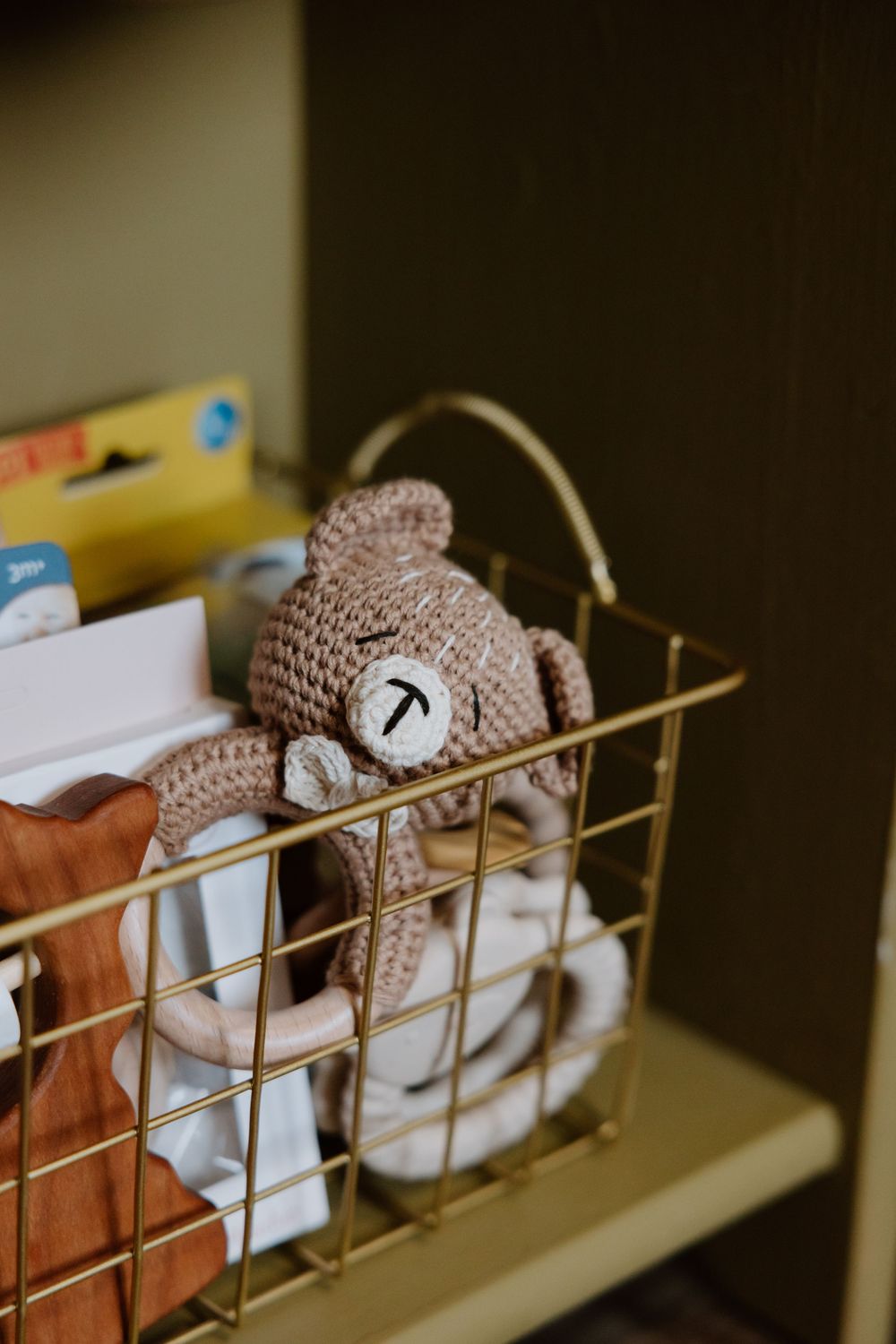 Knit stuffed animals and baby toys arranged neatly in a wire storage basket.