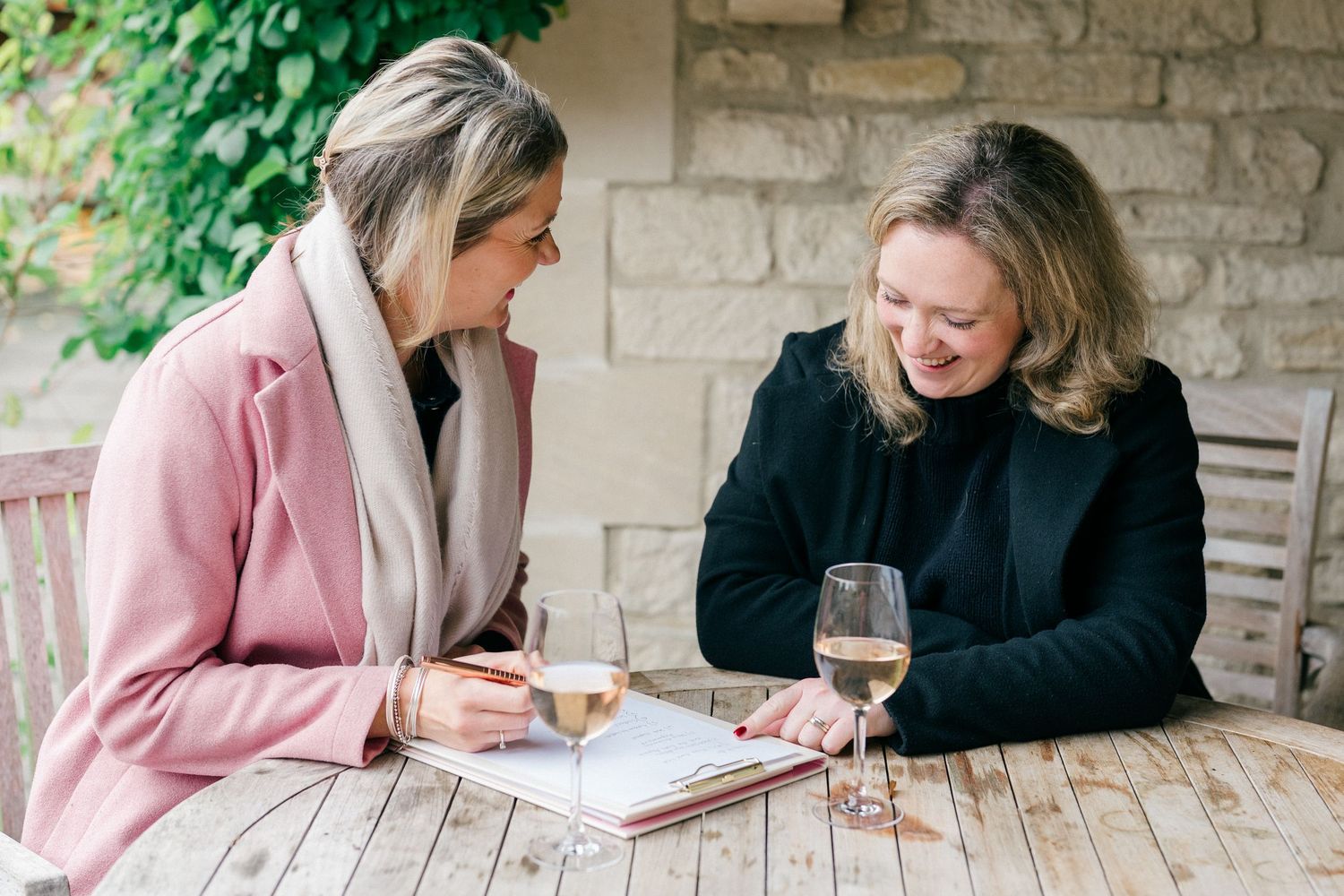 Personal brand photography of two businesswomen planning over drinks at an outdoor table