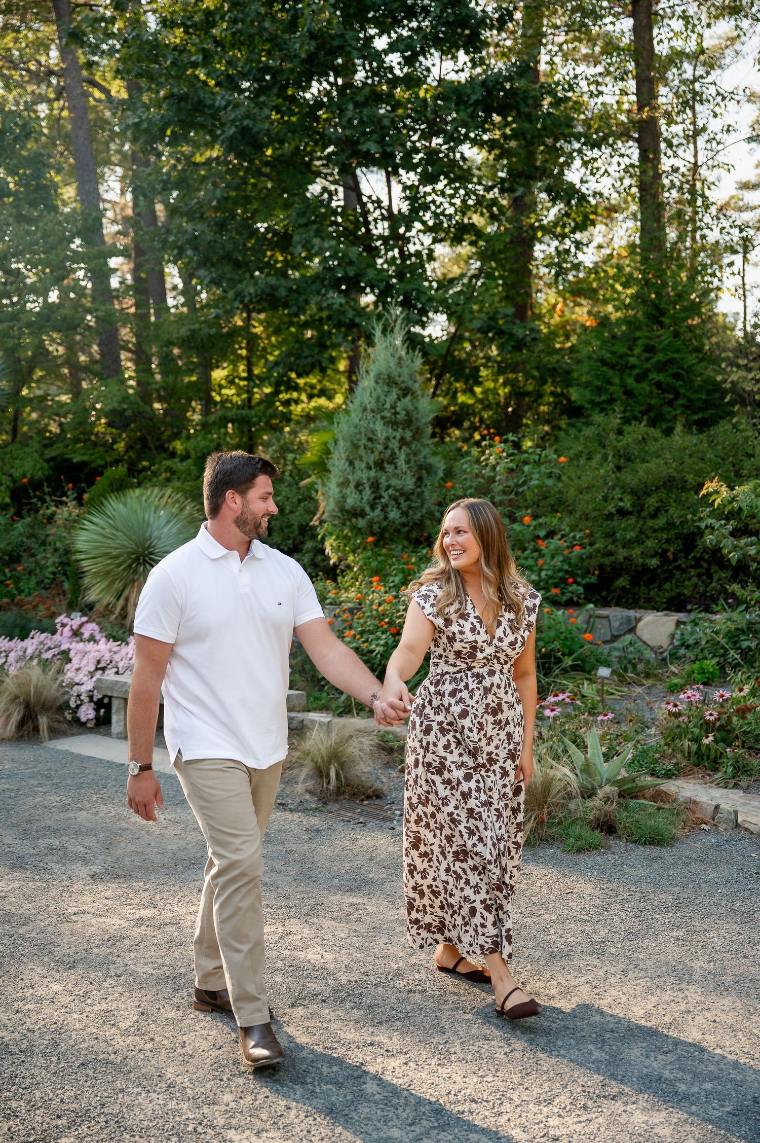 Couple shares playful moment together on garden path surrounded by lush greenery at sunset.