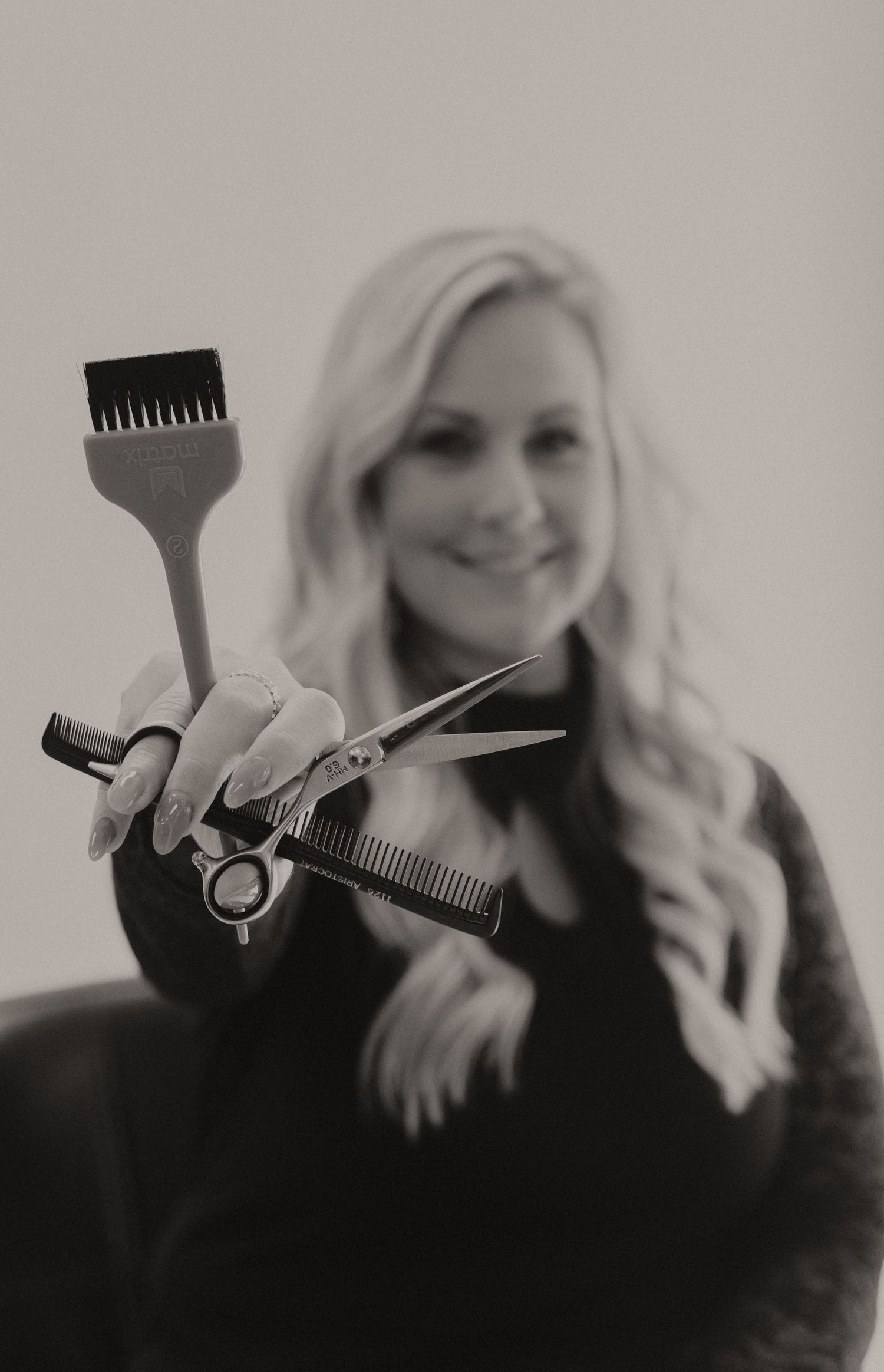 Black and white photo series showing hair styling tools and gestures in a soft, artistic composition.