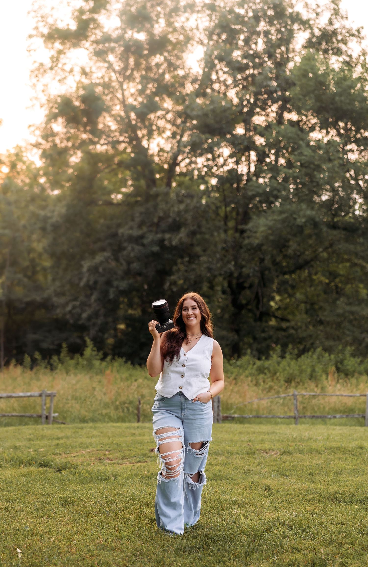 A photographer in ripped jeans and white top practices poses in an outdoor setting.