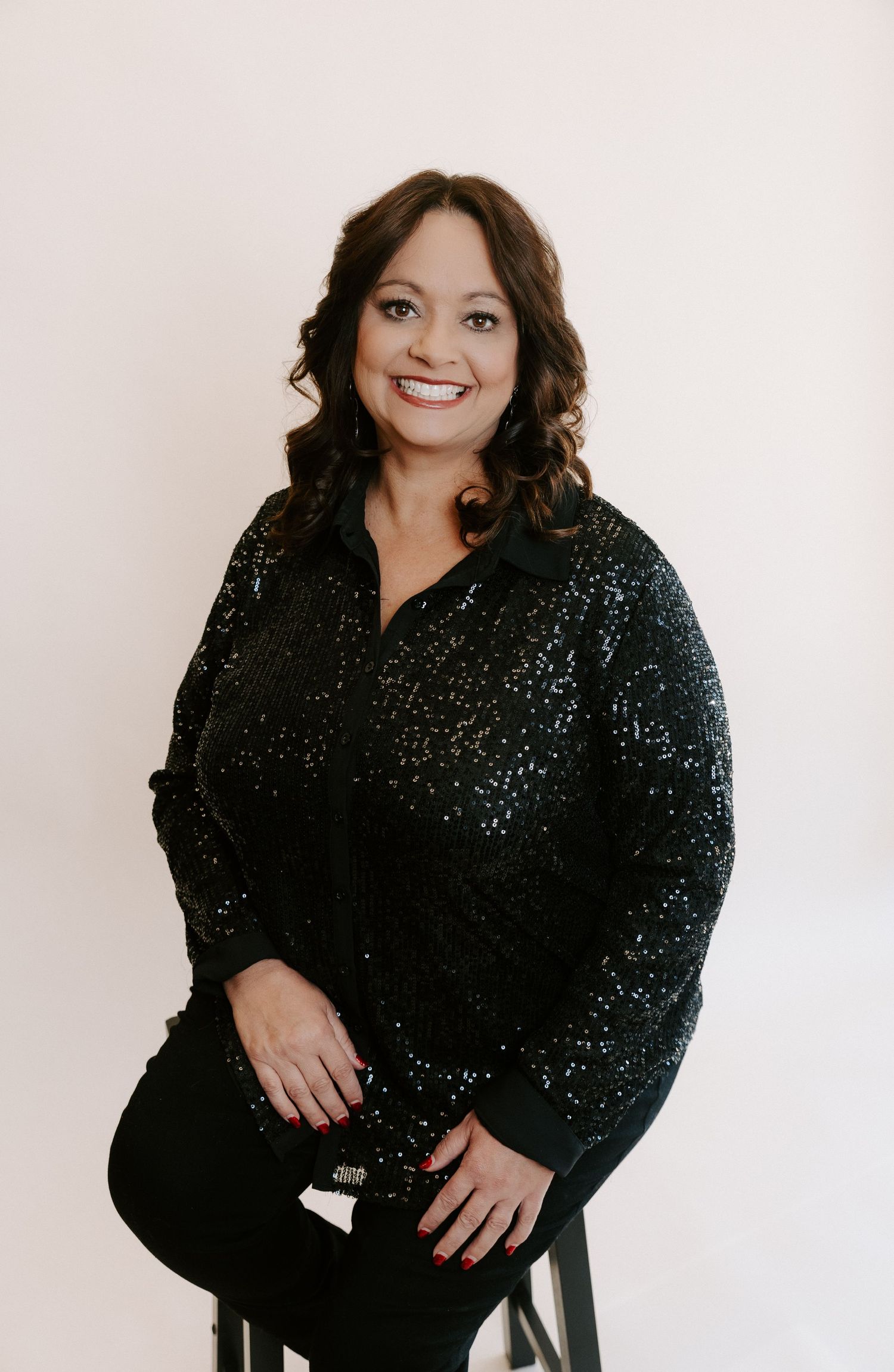 Professional studio portrait featuring a sparkly black sequined top against a light neutral background.