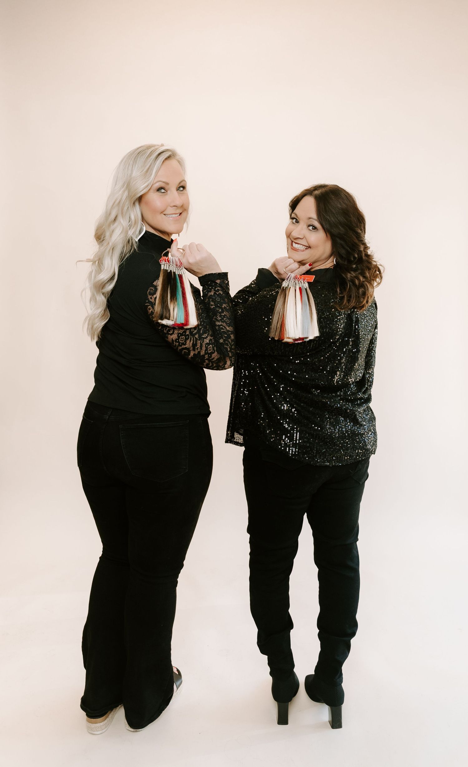 Two friends in black outfits pose playfully together against a light background in a series of candid shots.
