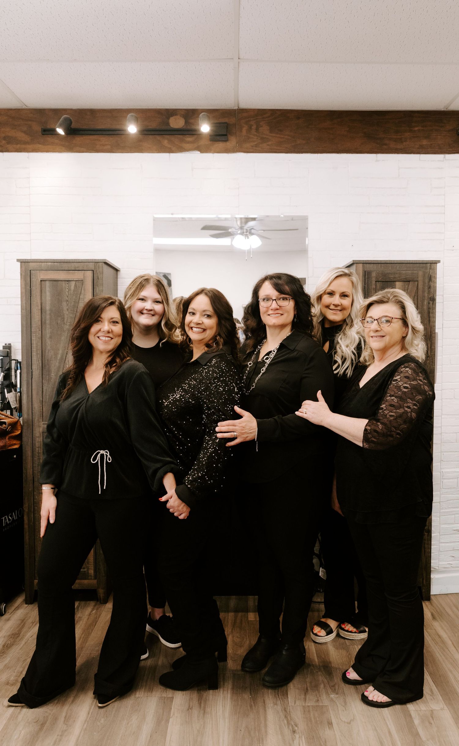 A group of women wearing elegant black dresses and formal attire pose together at an event.