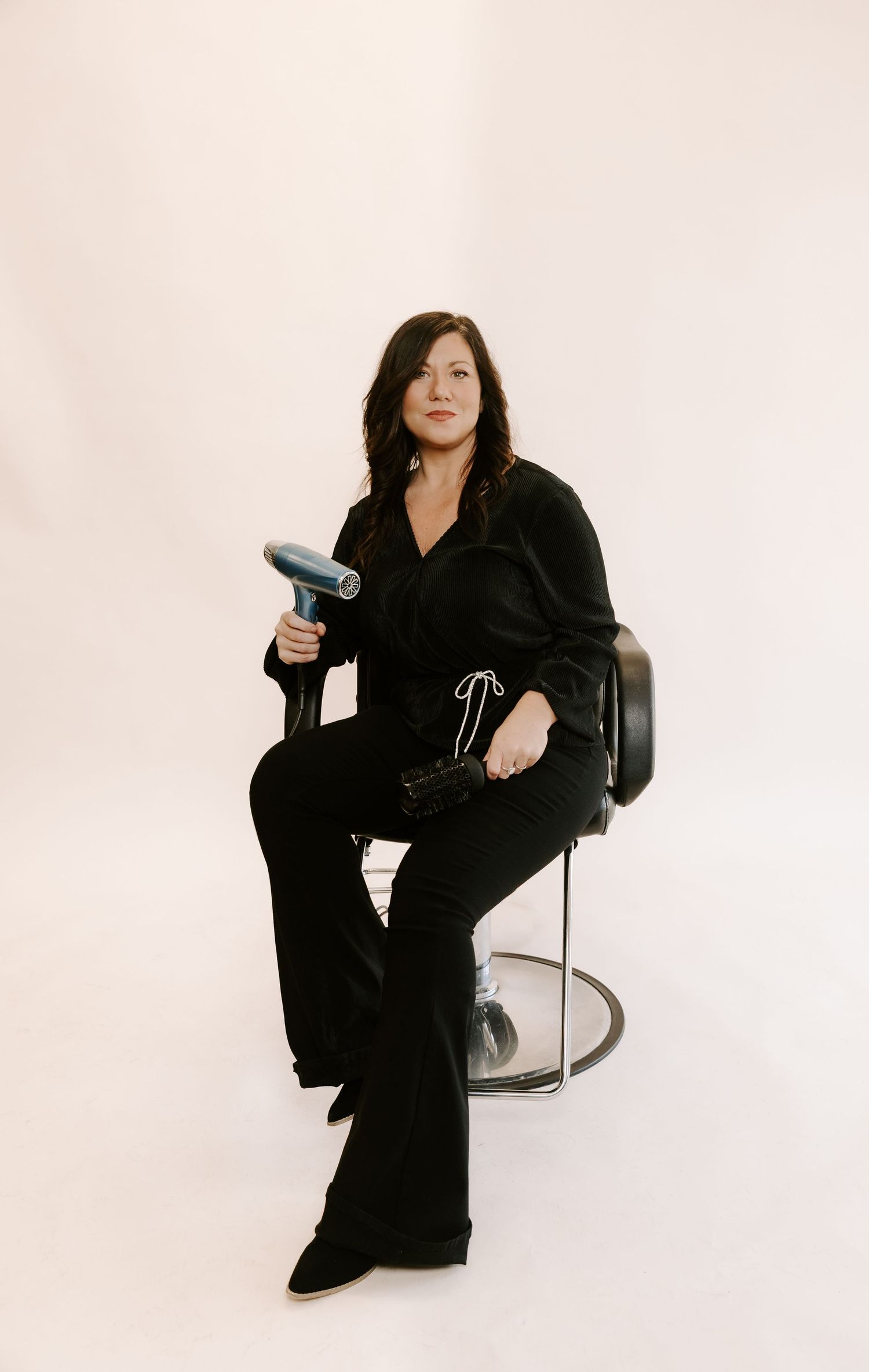 Figure in black attire poses dynamically against white backdrop in artistic fashion photo series.