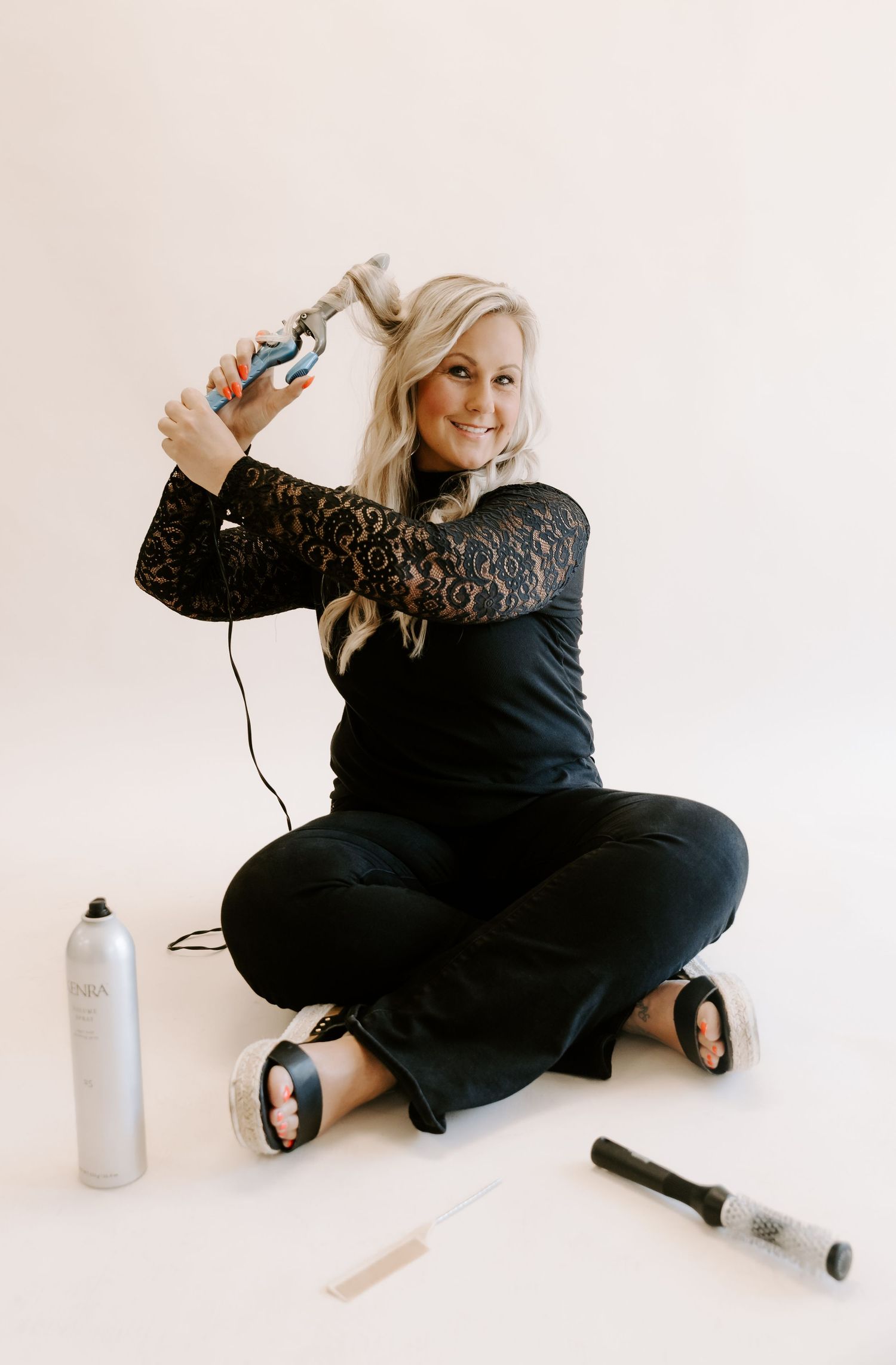 A person in a black outfit sits on a white floor in four sequential artistic poses with a white container nearby.