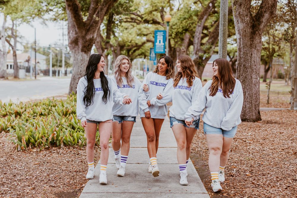 Group photo of friends in matching light denim and white sneakers walking outdoors.