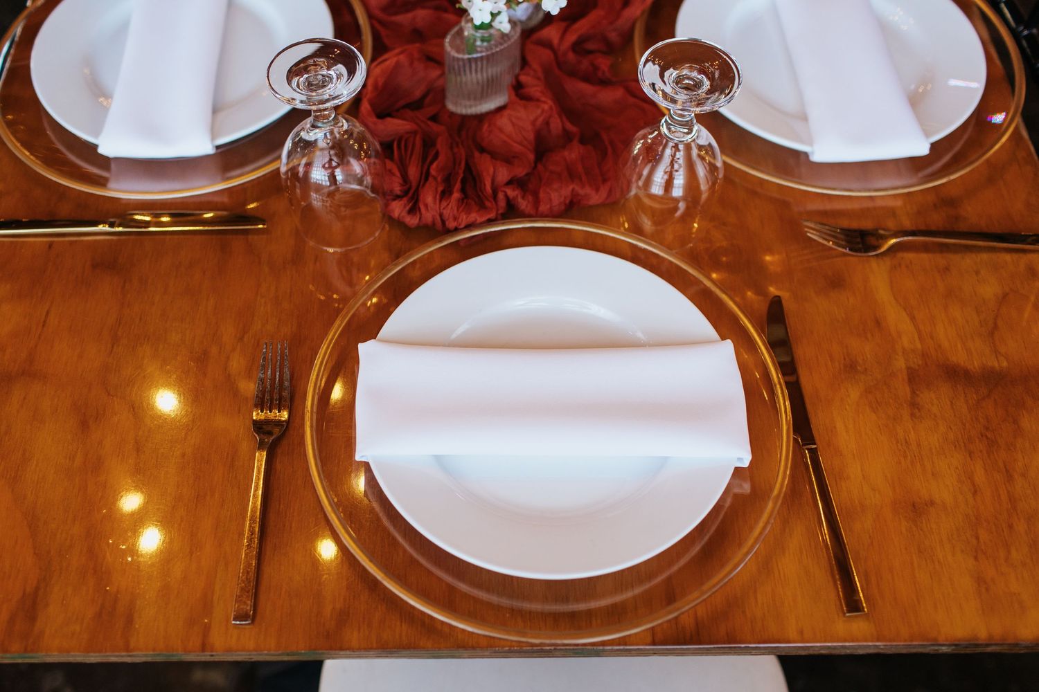 Formal place setting with gold charger plate, white napkin and crystal glassware.