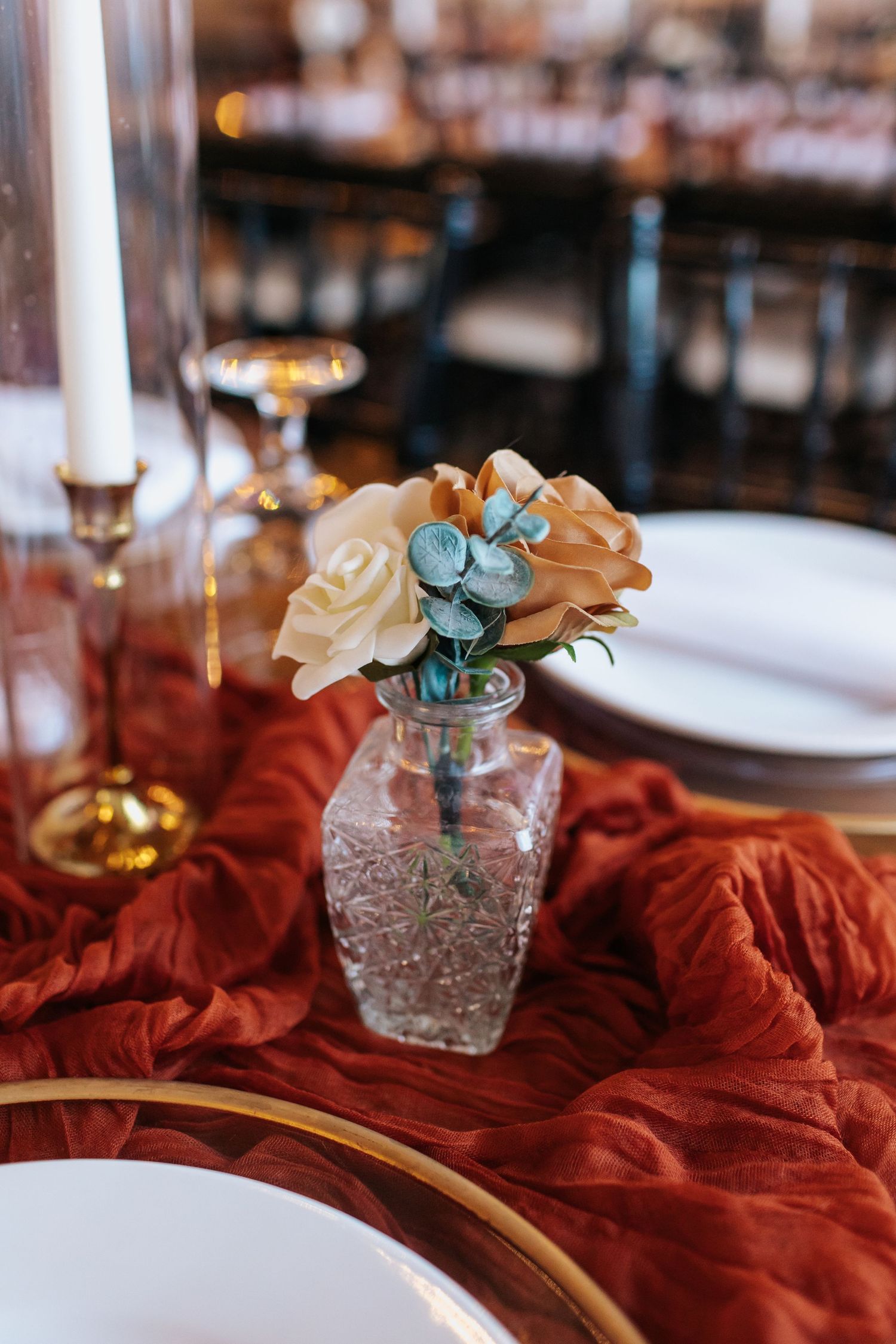 Small floral centerpiece with peach roses and eucalyptus in a textured glass vase.