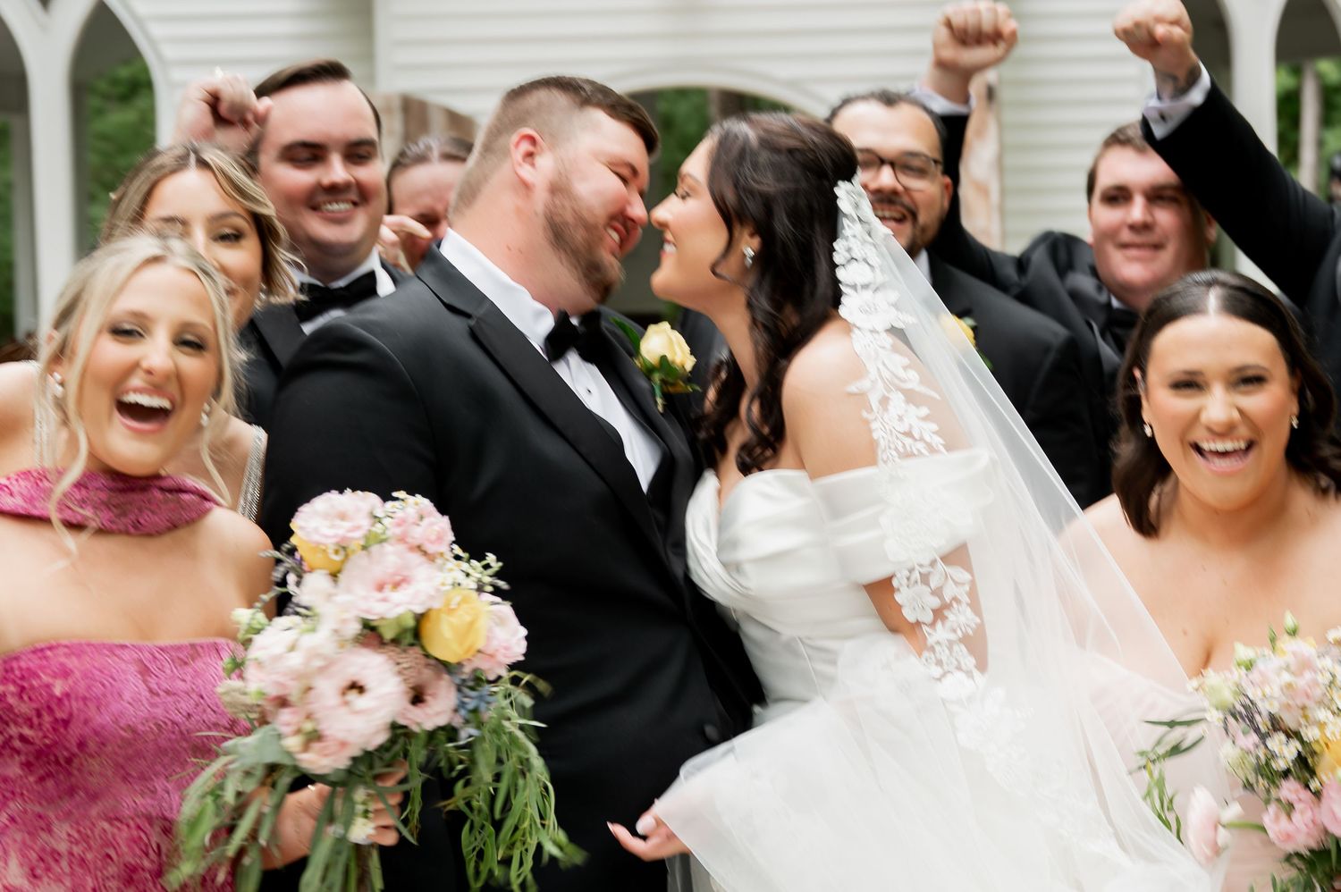 Wedding party celebrating with joyful expressions in an outdoor garden setting.