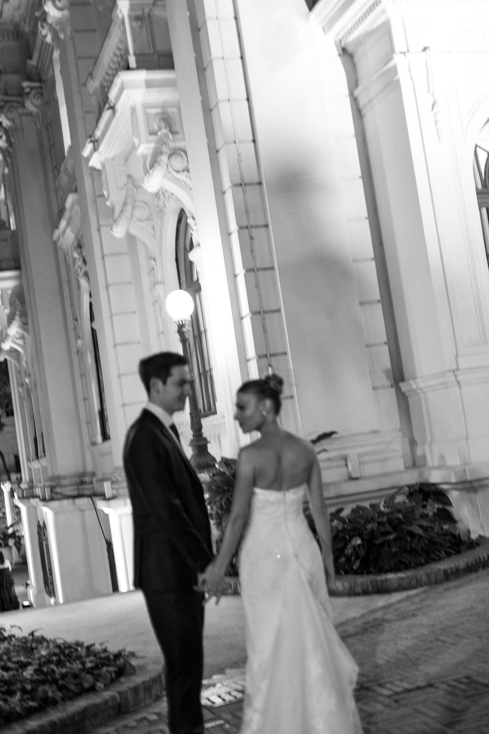 A bride and groom share a romantic moment under white archways during their wedding photoshoot.
