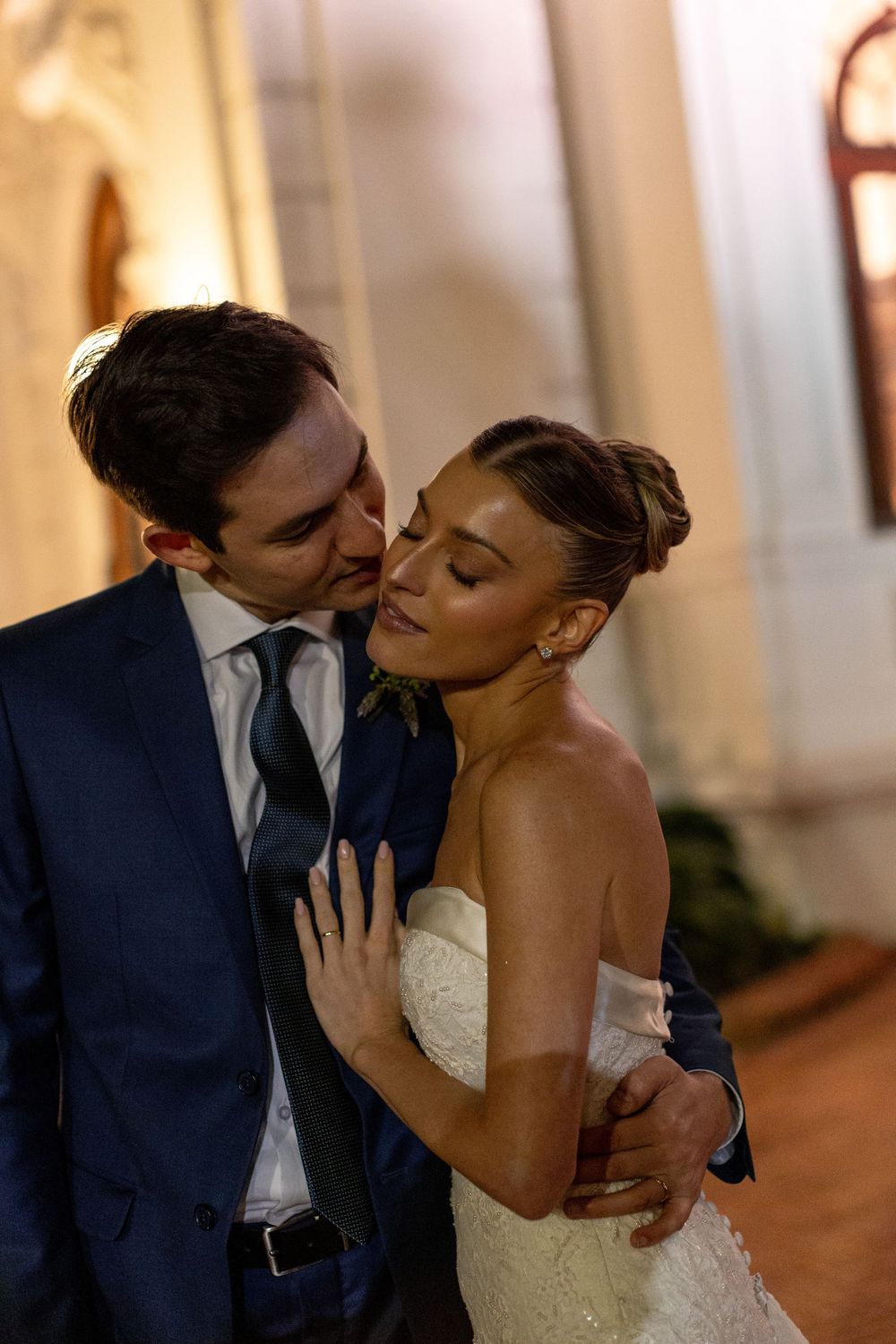 Romantic sequence of newlyweds sharing intimate kisses in an elegant indoor venue with white columns.