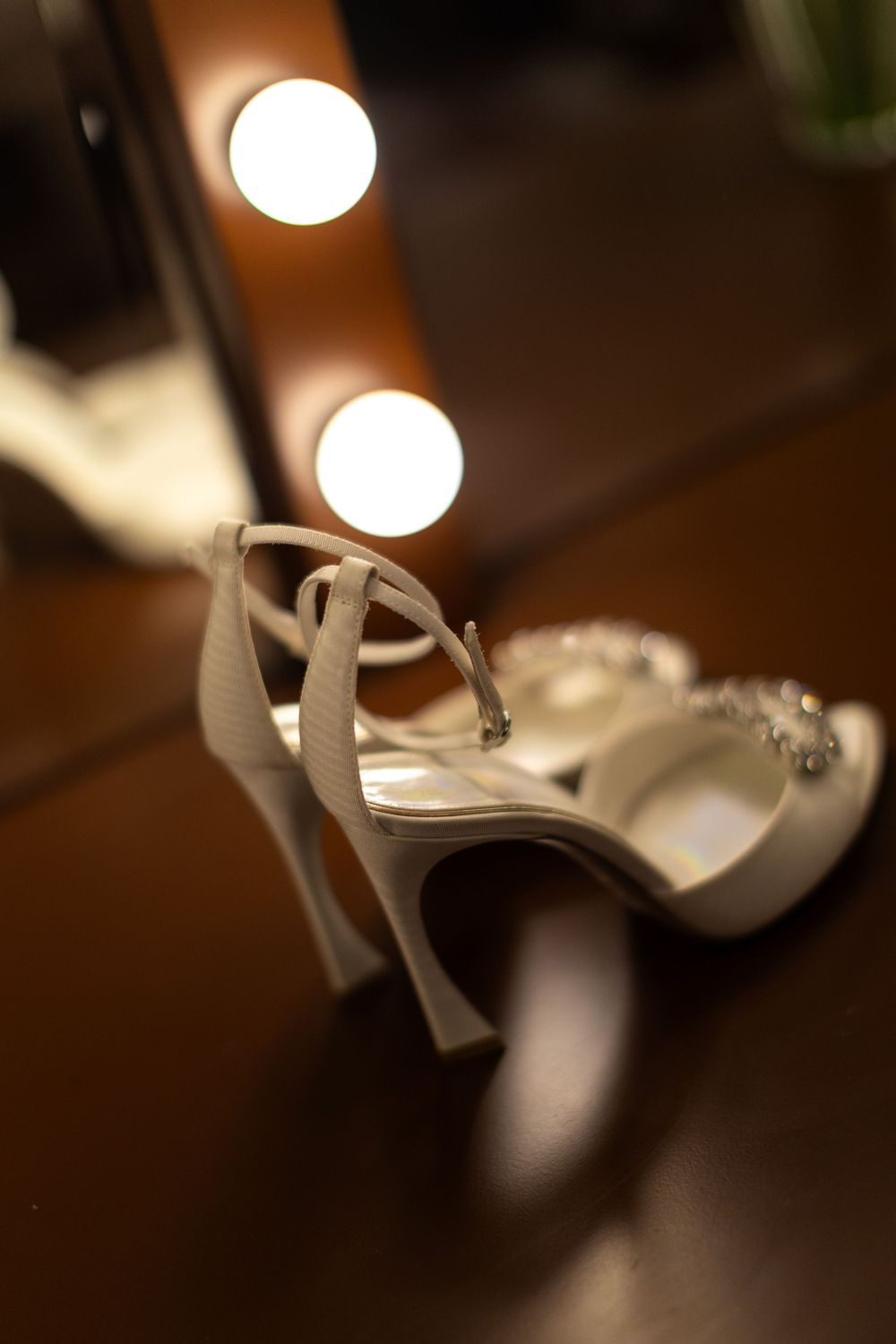 Close-up detail shots of elegant white bridal heels against a dark wooden background.